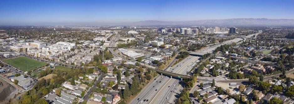 Photo of downtown San José area including freeways, buildings, homes, and a sports field
